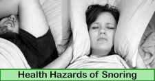 Health Hazards of Snoring. Picture of a caucasian male and female laying in bed sleeping. The female has her pillow pulled up over her ears.